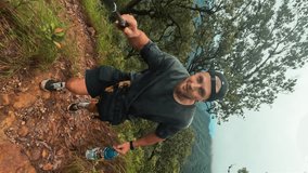 Young smiling carefree man recording selfie video blog enjoing hiking natural trail with amazing breathtaking mountain view, hiqh quality vertical 4K travel active lifestyle concept footage. Thailand.