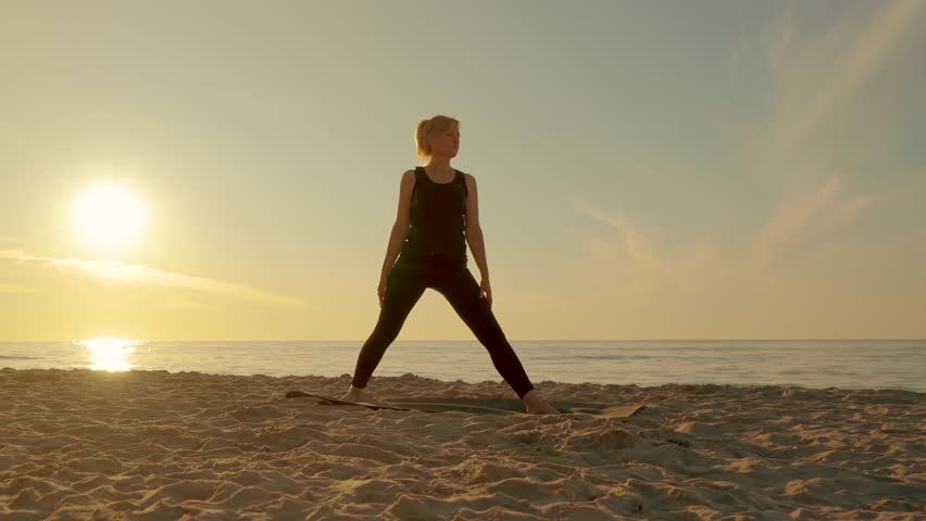 Adult woman doing yoga on sea beach sunset outdoor. Sport exercises and mental health. Healthy lifestyle, movement concept, meditation and wellbeing