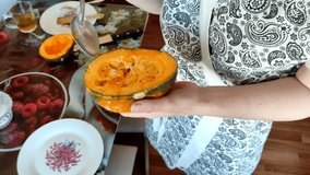 Woman removes seeds from ripe pumpkin with a spoon