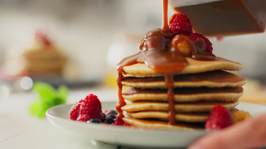 Fruit, a European woman diligently adds caramel to pancakes in the kitchen of a private home. Close-up european woman pouring caramel on pancakes with fruits new pancake recipes, flipping
 Royalty-Free Stock Footage #1107808249