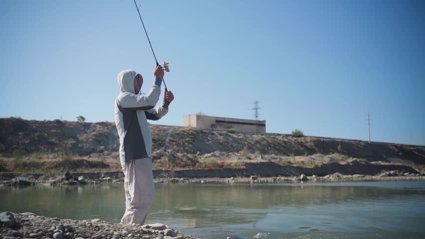 the fisherman catches fish on the shore with a spinning rod.