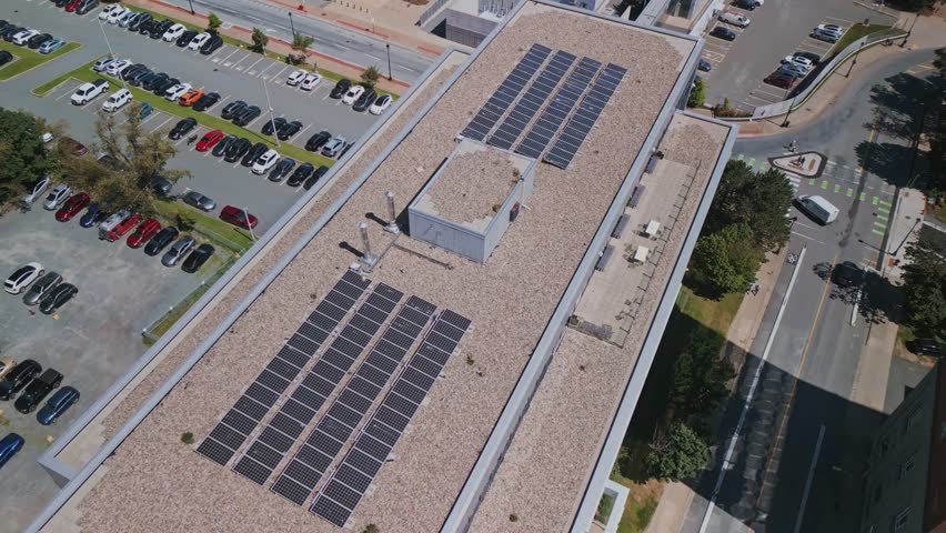 Drone shot of an array of solar panels installed on an apartment building in downtown Halifax, Canada. Drone view of a modern rooftop photovoltaic power system. Royalty-Free Stock Footage #1107814135
