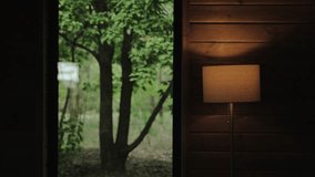 Window view from tiny wooden house, green forest outdoor, switched lamp with warm light near wooden wall, background.Closed window overlooking green garden, slow motion. - Powered by Shutterstock - Get 15% off with code: PIKWIZARD15