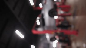 Vertical video. Blurred Background of Technicians Car Repair Center with Mechanics and Electric red Lift for Cars in Service Station.An electric lifter with a gray car. Defocused video.