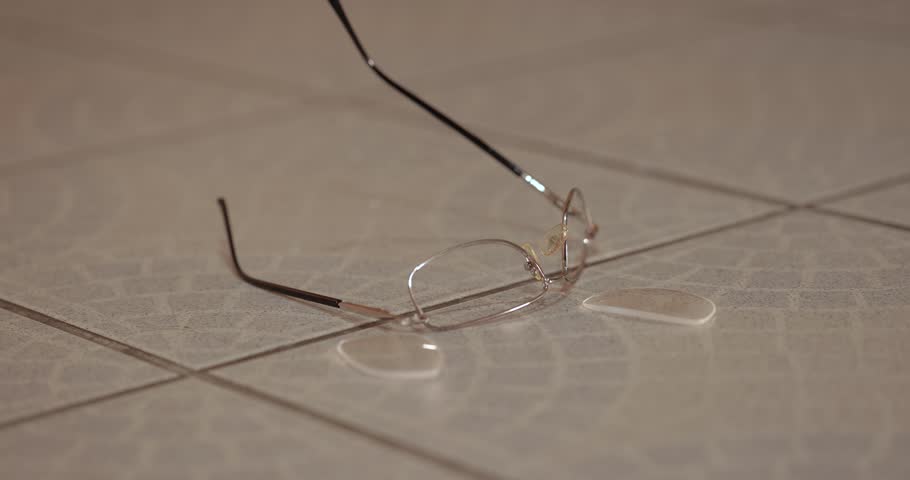 Hand searching for broken glasses fallen on the floor in pieces, destroyed, finding it in despair