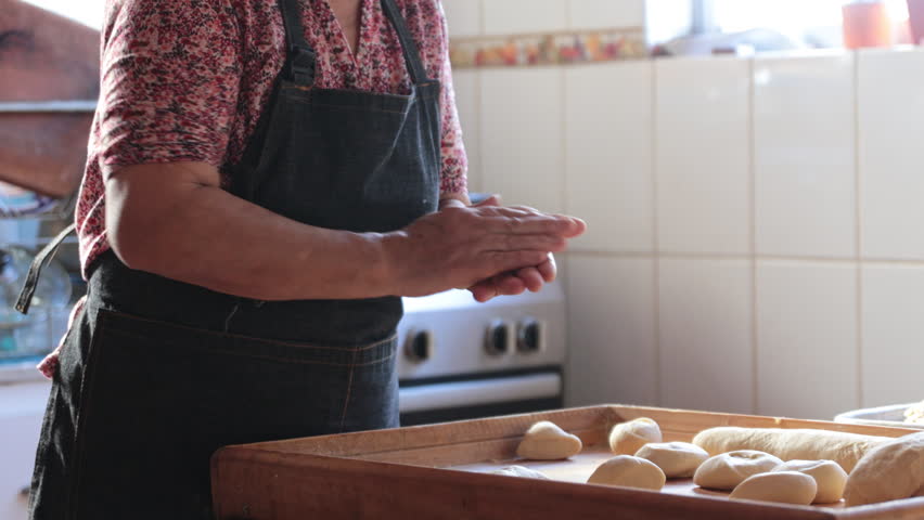 Candid scene of Unidentified Latina Woman Crafting Dough with Hands in Rustic Home Kitchen
