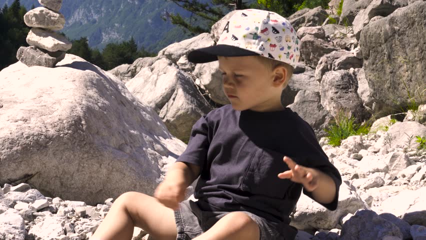 Kid In The Mountains Throwing Stones In The Water