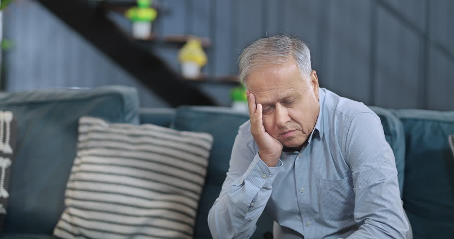 Worried retired old senior man sitting alone on sofa look away feel sorrow abandoned anxiety at home. Unhappy Indian middle aged male grieving think lonely depressed pensive suffering health problems Royalty-Free Stock Footage #1107833871