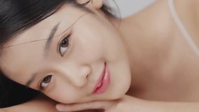 Close up portrait beautiful young Asian woman with healthy facial skin opening eyes over grey background. - Powered by Shutterstock - Get 15% off with code: PIKWIZARD15