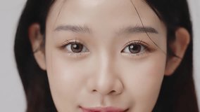 Close up portrait beautiful young Asian woman with healthy facial skin opening eyes over grey background. - Powered by Shutterstock - Get 15% off with code: PIKWIZARD15