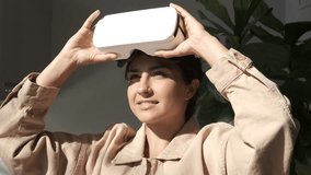 Stylish beautiful woman puts on vr glasses. Girl wearing modern virtual reality glasses. Future is now. Augmented Reality. Beautiful young female playing game in vr helmet and touch something. 4K - Powered by Shutterstock - Get 15% off with code: PIKWIZARD15