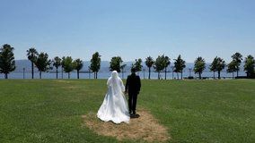 drone video of bride and groom walking to the seaside