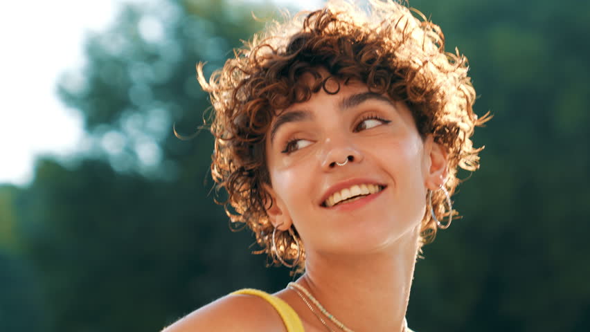 Young beautiful smiling hipster woman in trendy summer clothes. Cute teen model posing in the street background at sunset. Positive brunette female with curls hairstyle. Cheerful and happy  Royalty-Free Stock Footage #1107845617