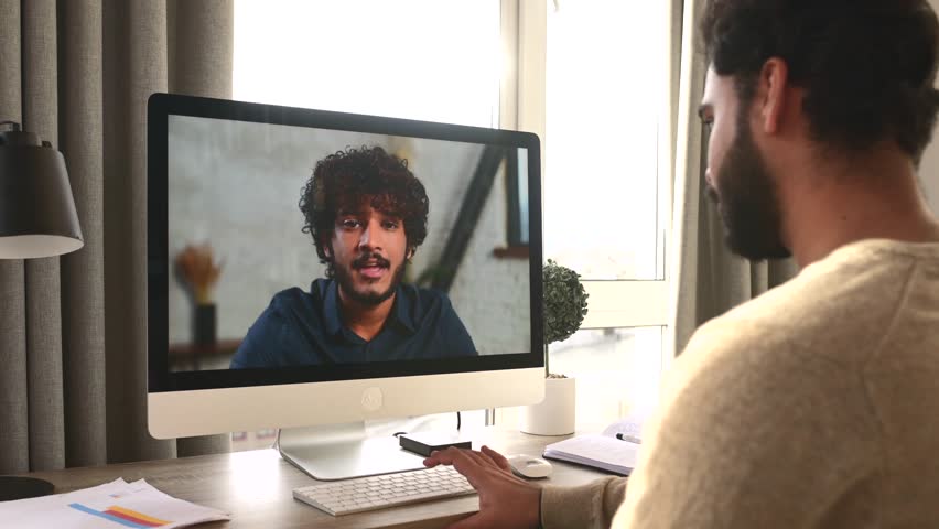 Two male colleagues greeting each other during video meeting. Multiracial business partners involved virtual conference. Back view male student takes an online language classes from teacher | Shutterstock HD Video #1107845681
