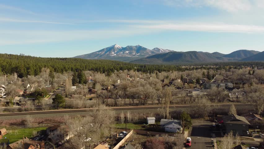 Ascending aerial view of Flagstaff in early spring, blue sky, beautiful scenery, snowcapped mountains. 4K resolution, 30fps. Royalty-Free Stock Footage #1107847341