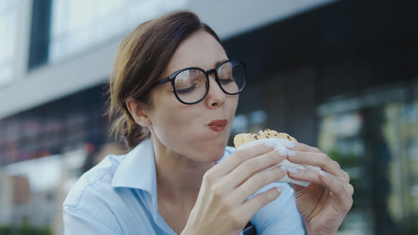 Hungry woman enjoying taste of sandwich, eating outdoor, failed her diet