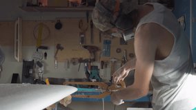 Male surfboard shaper making surfboard in his workshop. Hand shaping from blank. - Powered by Shutterstock - Get 15% off with code: PIKWIZARD15
