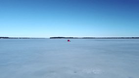 An aerial video of a box and fishing rod on a frozen lake on a sunny day