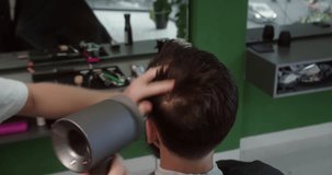 Hairdresser dries man's hair with a hair dryer in a beauty salon. High quality video. Men's hairstyle and haircut in the salon. Hair care with a hair dryer. 4K