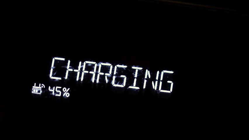 Charging text sign on an lcd screen of an electronic gadget glowing in the dark