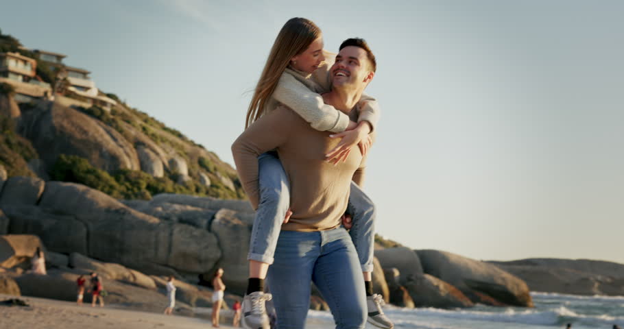 Piggyback, happy and a couple at the beach for a date, love and laughing together in Spain. Smile, summer and a pointing man and woman speaking with fun, bonding and walking by the sea for a holiday Royalty-Free Stock Footage #1107862411
