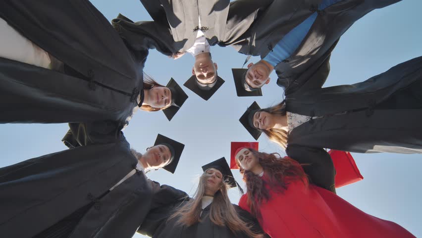 College graduates in a circle stand hugging each other. | Shutterstock HD Video #1107863221