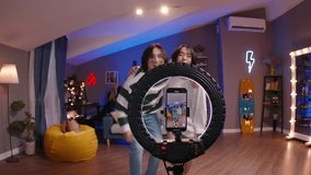 Two Gen Z Asian friends K-pop dancers record trending reels for social media. Funny dancing, filming performance on camera, living room, home studio, bloggers shoot video trend, virtual life concept