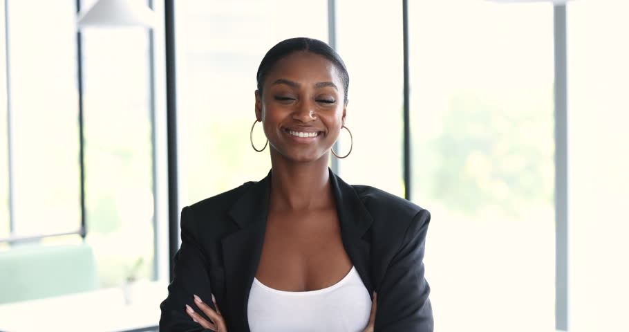 Smiling independent confident African business woman, company boss, executive manager head of corporation pose standing in office with arms crossed looking at camera. Ambitious businesswoman portrait