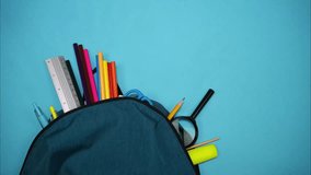 Colorful school supplies moving to green backpack on blue background. Back to school concept. Stop motion - Powered by Shutterstock - Get 15% off with code: PIKWIZARD15