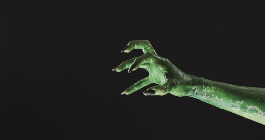 Video of halloween green monster hand with copy space on black background. Halloween, tradition and celebration concept.