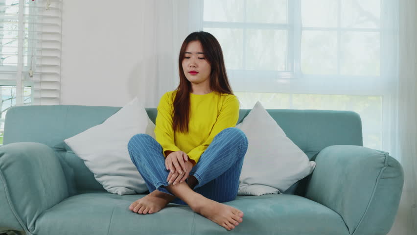 Lifestyle Asian young woman stretching her arms on sofa in the living room at home, happy female relaxing activity feeling lazy on weekend on couch, resting napping break Royalty-Free Stock Footage #1107887483