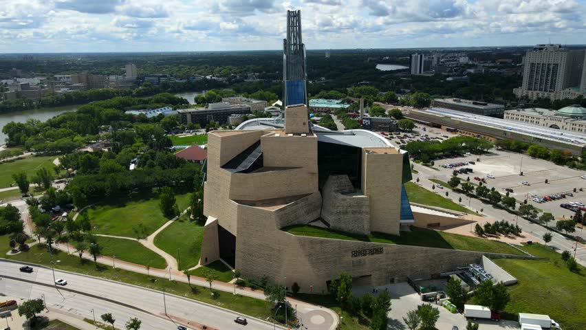Aerial shot drone orbits to right around iconic landmark in Winnipeg to reveal white suspension bridge over river