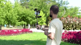 a young blogger walks in the park filming himself on smartphone