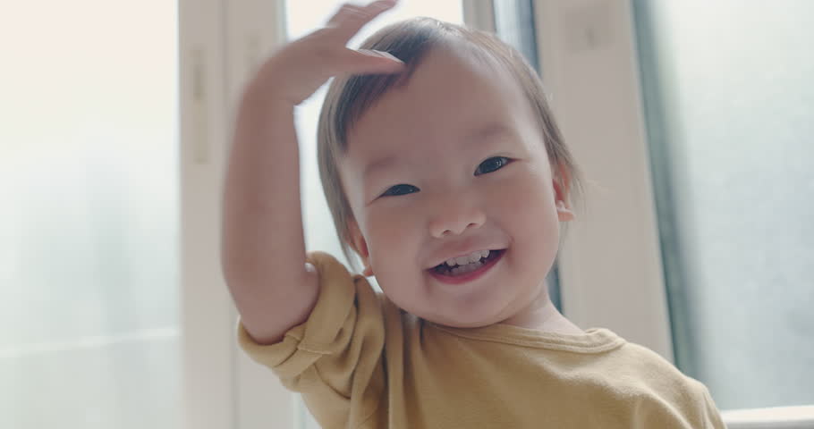 Portrait happy little cute Asian toddler child girl looking smiling to camera and dancing jump having fun on sofa in living room at home Royalty-Free Stock Footage #1107889265