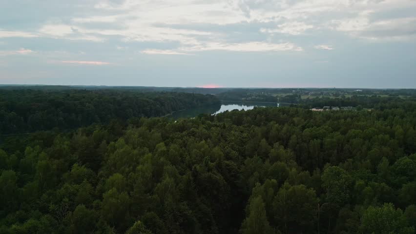 From an aerial perspective, capture the longest lake bathed in sunset hues, encompassed by a lush expanse of deep forest. Royalty-Free Stock Footage #1107890637