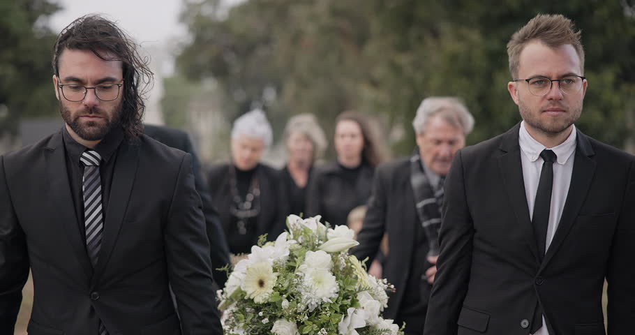 Pallbearers, men and walking with coffin at graveyard ceremony outdoor at burial place. Death, grief and group of people with casket at cemetery for funeral and family service while mourning at event Royalty-Free Stock Footage #1107891007