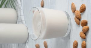 Person taking a glass with almond milk, Close-up video of vegan drink made of almond nuts placed on white table, 4k vertical video, slow motion footage 
