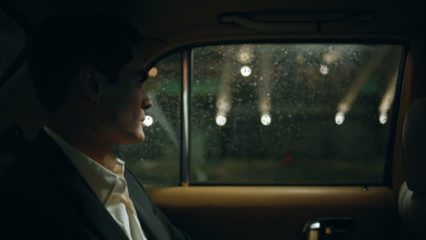 Stylish businessman commuting automobile at night town closeup. Elegant man looking window enjoying rainy weather evening. Serious lawyer resting taxi backseat thinking in city street lights view car  Royalty-Free Stock Footage #1107893439