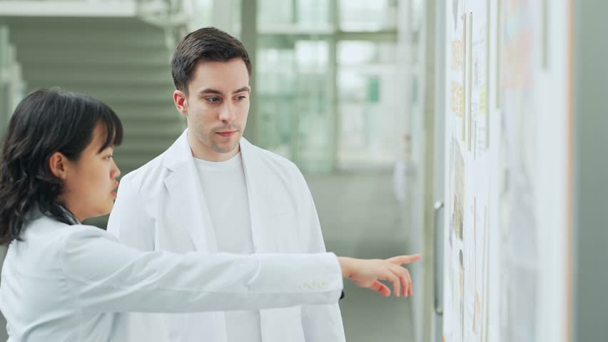 Multinational group in white coats having a conversation in a research facility. Royalty-Free Stock Footage #1107894593