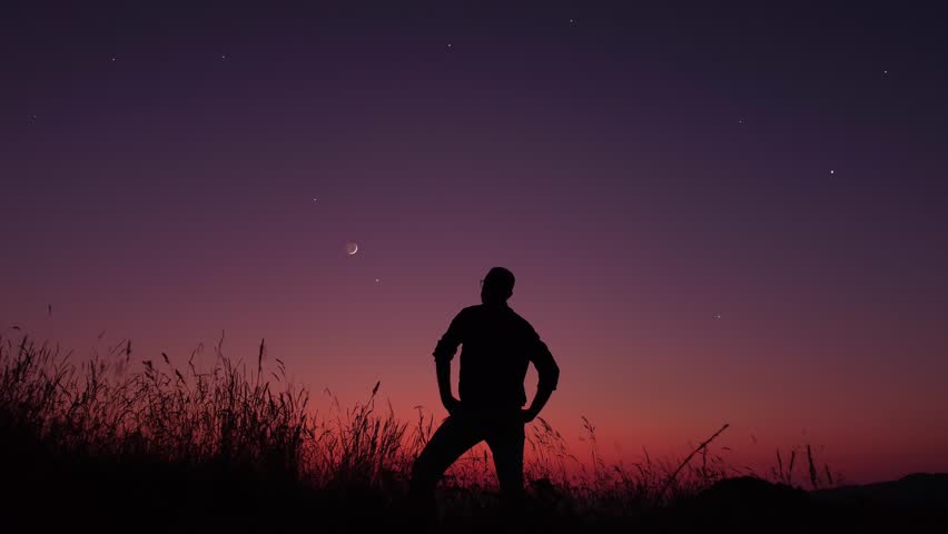 Man looking at the starry skies, crescent Moon and shooting star in blue hour twilight time.