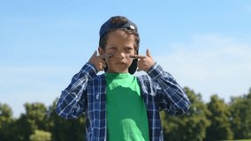 Portrait of determined cute preadolescent black boy baseball player in cap applying eye black strips underneath his eyes, looking with serious expression, showing readiness for game outdoors. - Powered by Shutterstock - Get 15% off with code: PIKWIZARD15