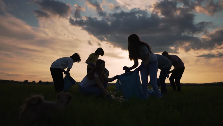 Volunteer cleaning up plastic waste. Silhouette of a group of people together collect plastic garbage in bags. Plastic garbage teamwork of volunteers with garbage bags in nature. plastic in nature Royalty-Free Stock Footage #1107898109