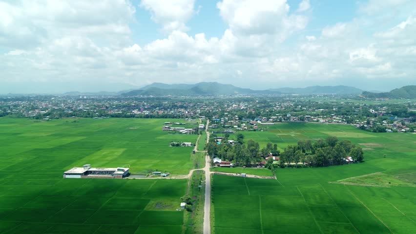Aerial shot of village in North east India with lush green farm surrounded alongside a narrow road with mountains and houses in backdrop Royalty-Free Stock Footage #1107898873