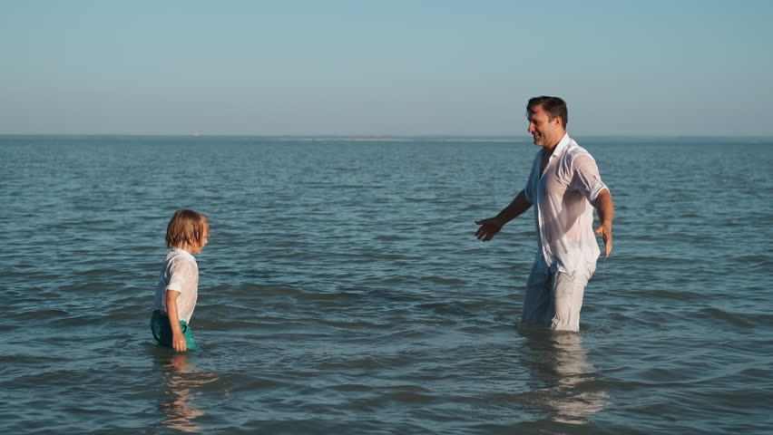 Father and son spray each other with water while swimming in the ocean.