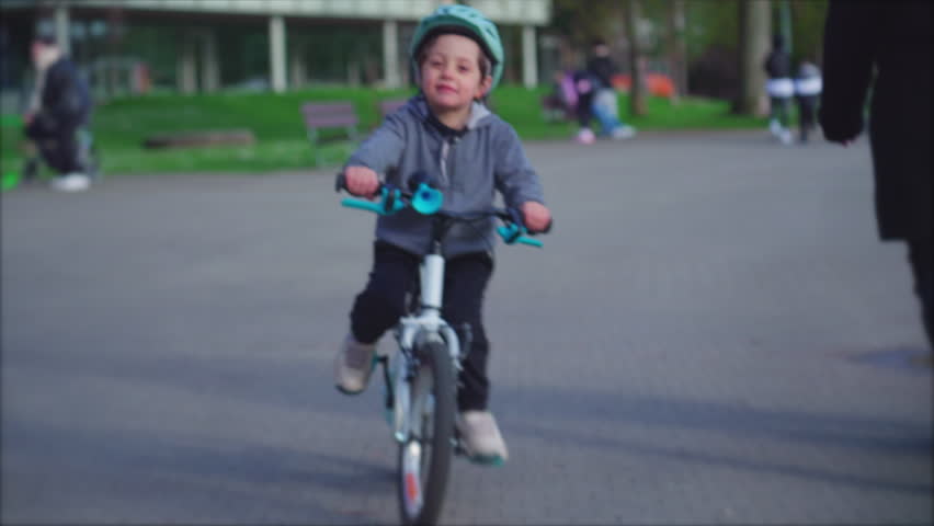 Energetic little boy riding bicycle outdoors at park, child wearing protective helmet rides bike