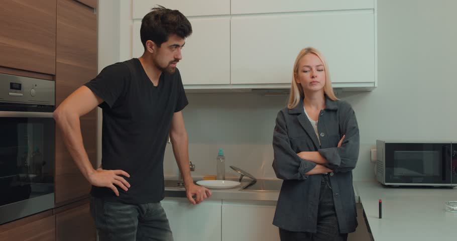 Tired frustrated fair-haired emotional wife arguing blaming upset man of problems, jealous woman shouting at sad male, family fight and controlling boyfriend, disrespect. in kitchen Slow motion Royalty-Free Stock Footage #1107908131