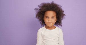 Portrait of cheerful charming cute little African American girl blowing kiss isolated over purple background in studio. Childhood lifestyle concept Slow motion Love Emotions I love you