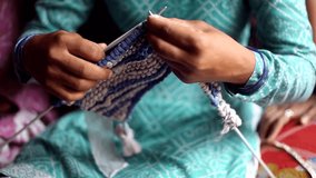 Close-up video of a woman hands knitting foot mat at home in winter.
