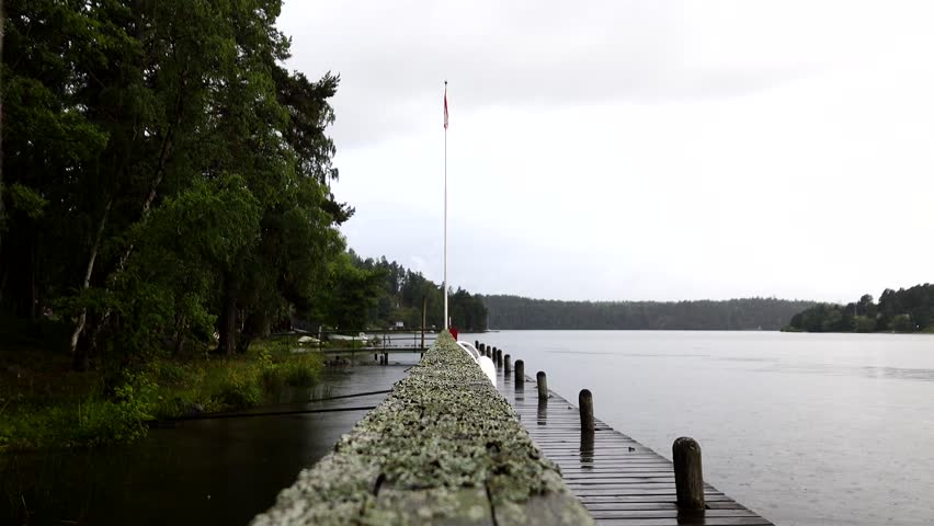 Stockholm, Sweden A man walks on a wooden dock on Lake Malaren in the rain with an umbrella. 