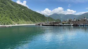 In the video, Fenniaolin Fishing Port in Yilan City, Taiwan is surrounded by mountains. Turquoise sea water, beautiful blue sky and white clouds.